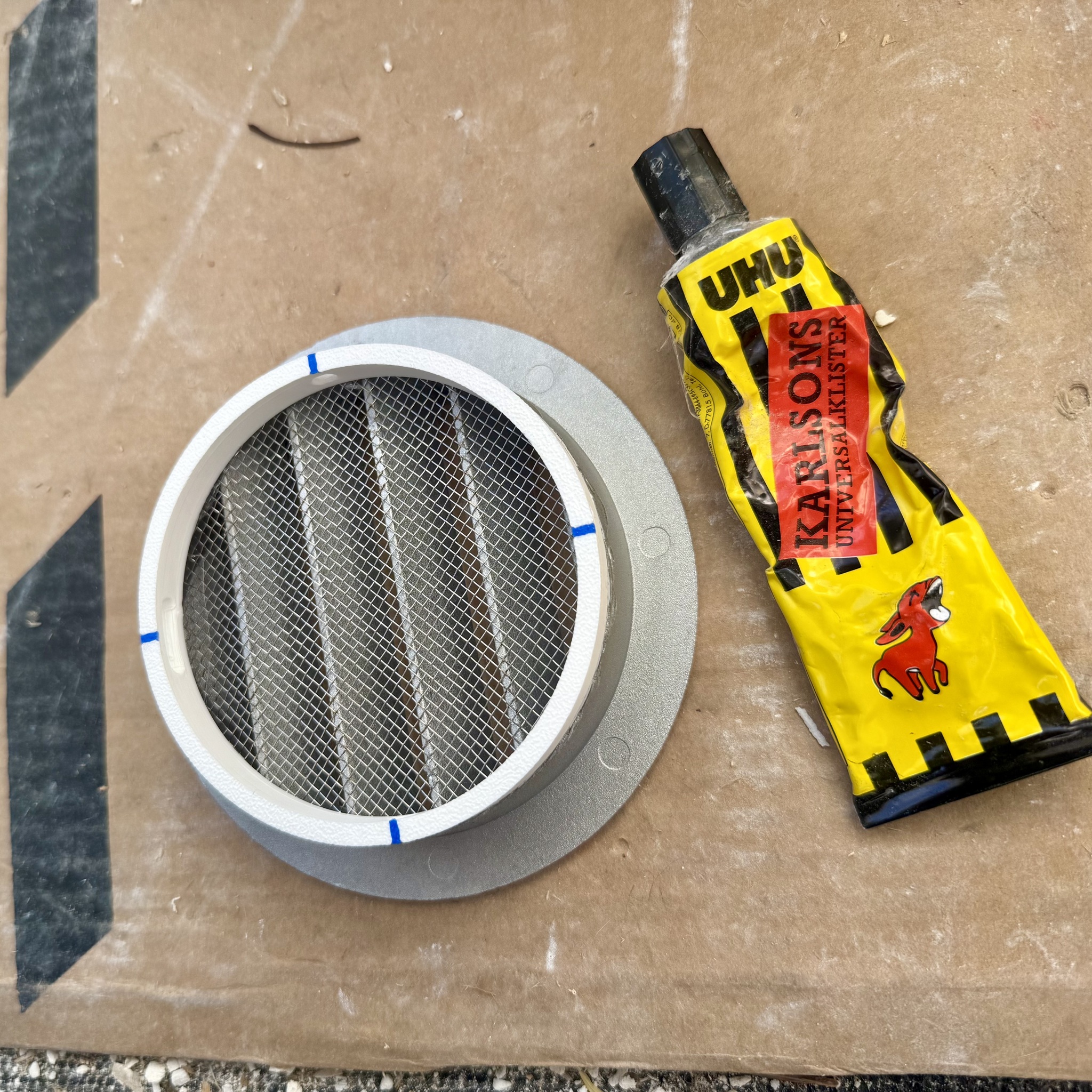 Ventilationsgaller med fästring bredvid en tub Karlssons Klister